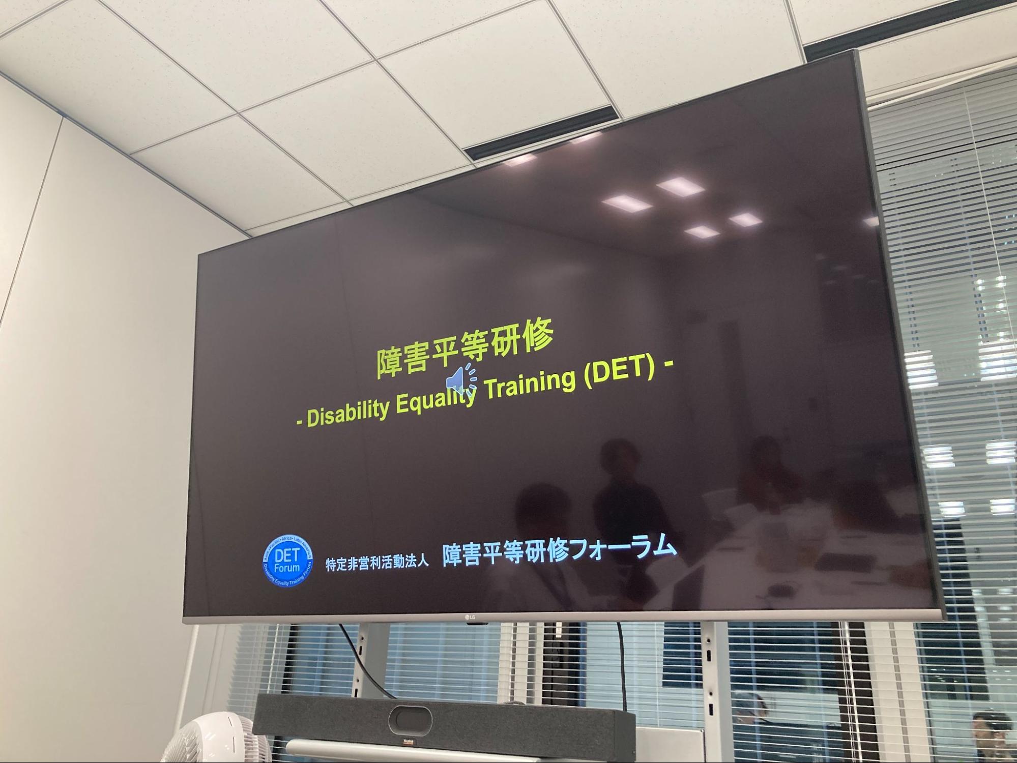 明るい会議室で、お菓子や飲み物を囲みながら、5名の参加者がリラックスした様子でテーブルを囲んでいる研修会場。
